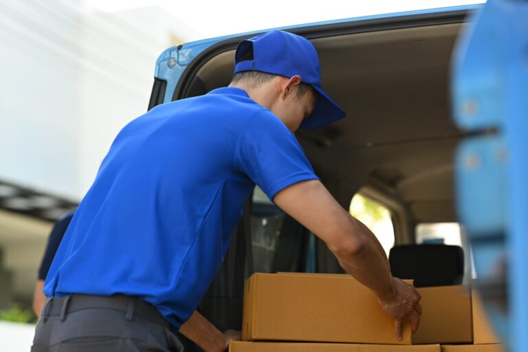 Shot of delivery men unloading cardboard boxes from cargo van.
